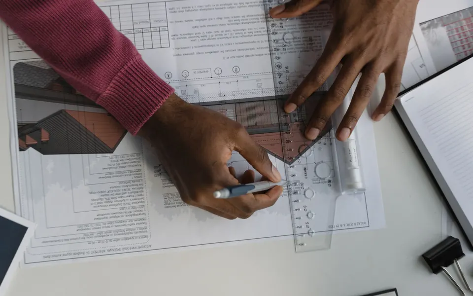 مراجعة مخططات هندسية وقياسات على طاولة عمل